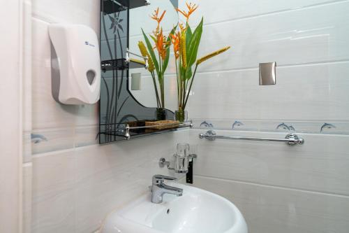 a white bathroom with a sink and a mirror at Janes' Serenity Guesthouse in Anse a La Mouche