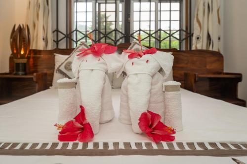 a group of towels with red flowers on a bed at Janes' Serenity Guesthouse in Anse a La Mouche