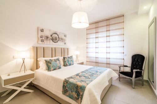 a bedroom with a large bed and a chair at ALBUFEIRA (OLD TOWN) VERASOL AA - THE LUXURY STAY in Albufeira