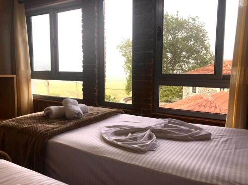 een bed met een knuffeldier erop in een kamer met ramen bij Villa Muzhaqi in Nivicë