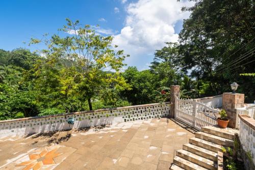 a stone fence with stairs and trees in the background at Janes' Serenity Guesthouse in Anse a La Mouche