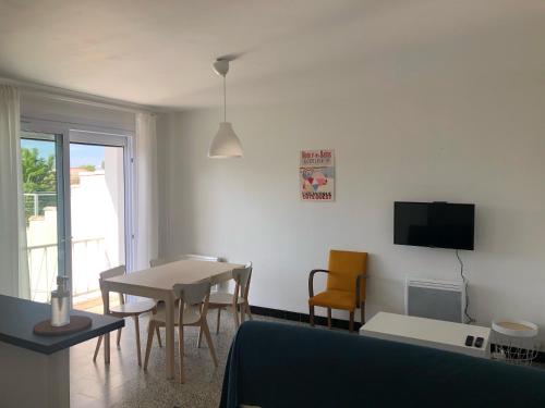 un salon avec une table, des chaises et une télévision dans l'établissement La Luciole, Ronce les Bains, à Ronce-les-Bains