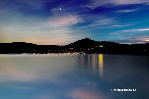 a large body of water with a mountain in the background at APPARTAMENTO OSIDE HOUSE alloggio turistico in Trevignano Romano
