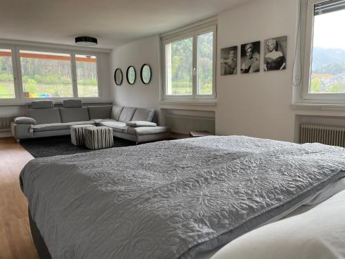 a bedroom with a bed and a couch and windows at Skyloft Apartment Feldkirch in Feldkirch