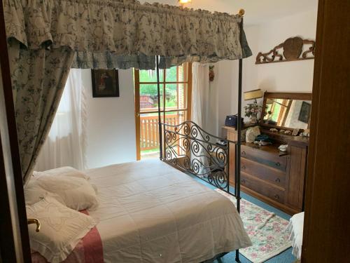 a bedroom with a bed and a dresser and a window at Siusi Sciliar Apartment in Siusi