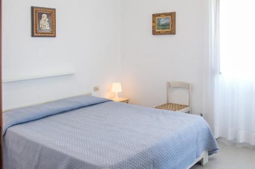 アルバ・アドリアティカにあるAppartamenti Vistamareの白いベッドルーム(青いベッド1台、椅子付)