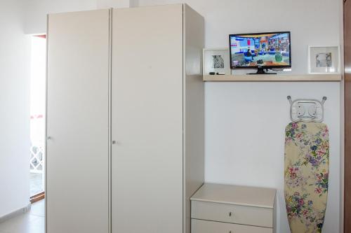 アルバ・アドリアティカにあるAppartamenti Vistamareの白いキャビネットと棚の上にテレビが備わる客室です。
