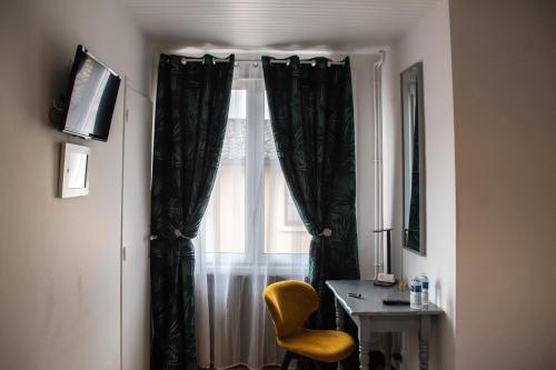 a window with black curtains and a table and a chair at Hôtel & Gastronomie - La Table de l'Europe in Villeréal