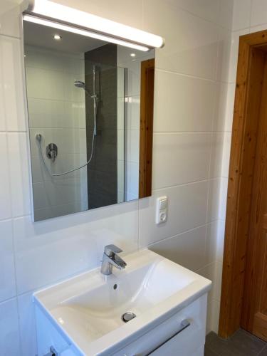 a white bathroom with a sink and a mirror at Ferienhaus Veronika mit 2000qm Garten und Bergblick in Unterammergau