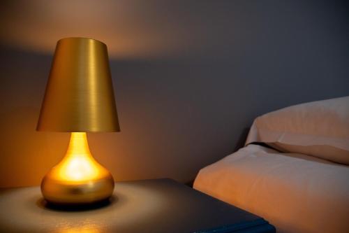 a lamp sitting on a table next to a bed at Hôtel & Gastronomie - La Table de l'Europe in Villeréal