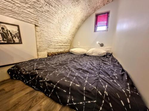 une chambre avec un lit dans un mur de briques dans l'établissement Wifi atypique Appartement Vieux Banyuls sur Mer, à Banyuls-sur-Mer