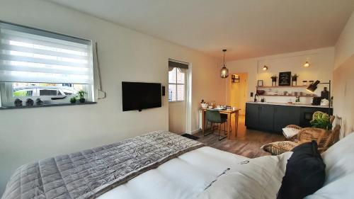 a bedroom with a bed and a window and a kitchen at B&Be Happy in Berg en Terblijt