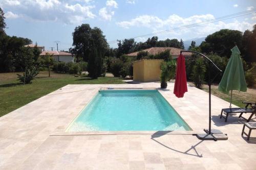 une piscine dans une cour avec un parasol dans l'établissement Suite spacieuse avec accès piscine, à Ghisonaccia
