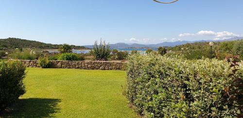 a garden with a stone wall and green grass at Residenze Coda Cavallo in San Teodoro