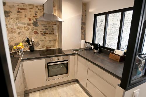 une cuisine avec des armoires blanches et un four à plaques de cuisson dans l'établissement Meublé de tourisme, Les chambres du Beffroi, à Boulogne-sur-Mer