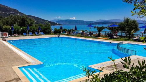 einen großen blauen Pool mit Blick auf das Wasser in der Unterkunft Barbati Bay Elegant Beach Apartments by Hotelius in Barbati