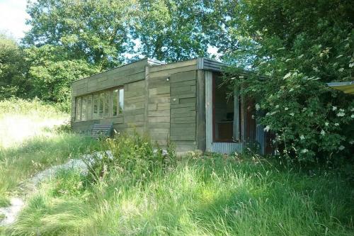 a small shack in the middle of a field of grass at Stags View,Unique eco cabin, Dartmoor views in South Brent