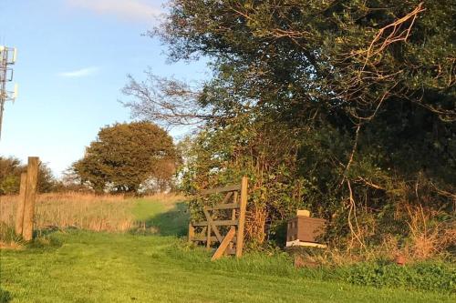 a wooden gate in a field next to a tree at Stags View,Unique eco cabin, Dartmoor views in South Brent