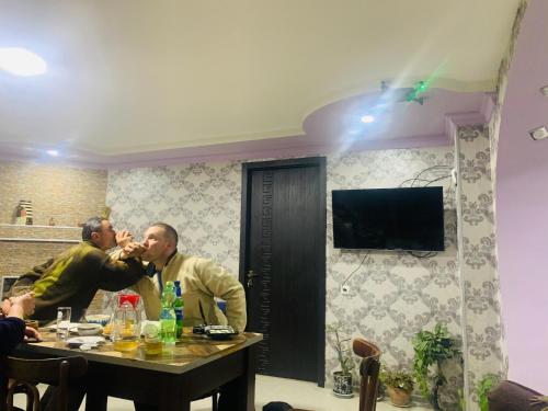 two men sitting at a table in a room at Butichi Guest House in Chiatʼura