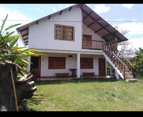 a large white house with a staircase in a yard at Cabaña El Trebol in San Agustín