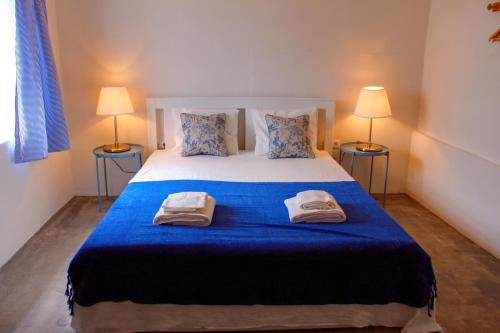 a bedroom with a large blue bed with two lamps at The House in São Roque do Pico