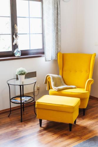 a living room with a yellow chair and a table at Vila Olívia - Apartmán Olívia 1 in Ružomberok