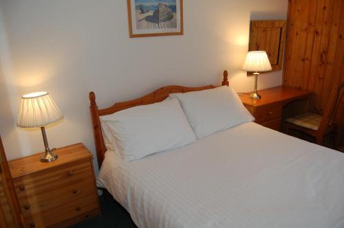 a bedroom with a white bed with two lamps at Woodland Chestnut Lodge in Killin