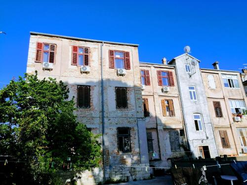 an old stone building with red windows and a tree at Pula Center Arena Belvedere Apartments and Rooms in Pula