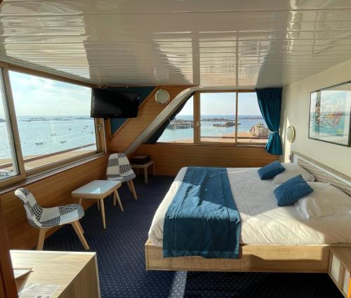 a bedroom on a yacht with a bed and a balcony at Hotel De La Mer in Trégastel