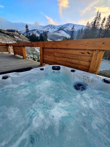 a jacuzzi tub with a fence and mountains at Chalet SNOW in Demanovska Dolina