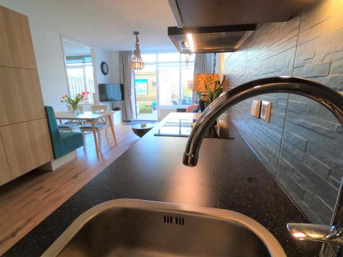 a kitchen sink with a faucet and a living room at Casa Nuestra in Egmond aan Zee
