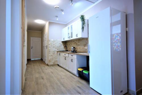 a kitchen with white cabinets and a wooden floor at Pensjonat Stary Busko Zdrój in Busko-Zdrój