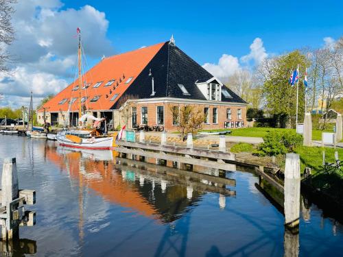 una casa con muelle y barcos en el agua en Verblijf bij Bynt en Sneek