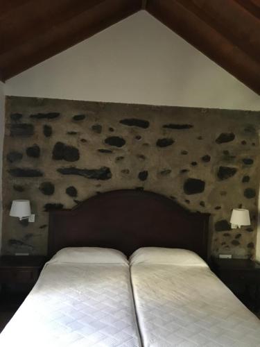a bed in a bedroom with a stone wall at Hotel Rural Ibo Alfaro - OFFLINE HOTEL in Hermigua