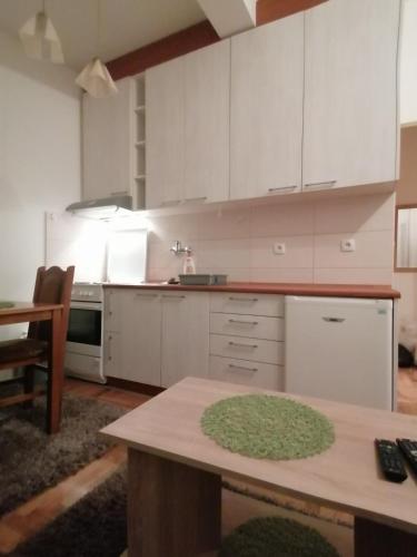 a kitchen with white cabinets and a wooden table at Jaca 2 in Požarevac