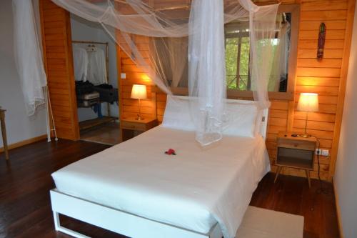 a bedroom with a white bed with a canopy at Eden Valley Ecolodge and Farming in Madalena
