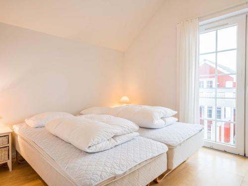 a white bedroom with a bed with white sheets and a window at 6 person holiday home in Blåvand in Blåvand
