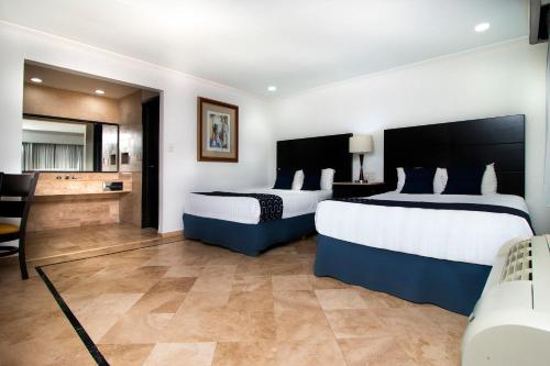 a hotel room with two beds and a living room at Capital Urban in Los Mochis