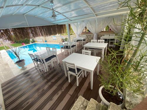 a patio with tables and chairs and a pool at Alacati Eldoris Butik Hotel in Alaçatı