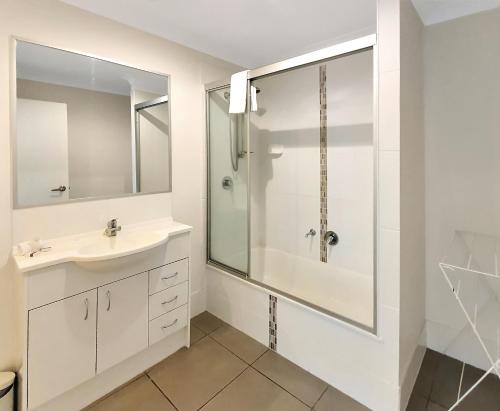 uma casa de banho branca com um lavatório e um chuveiro em Lillypilly Resort Apartments em Rockhampton