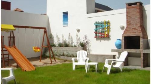 un patio trasero con 2 sillas y un columpio en Complejo Mare Mare en Villa Gesell