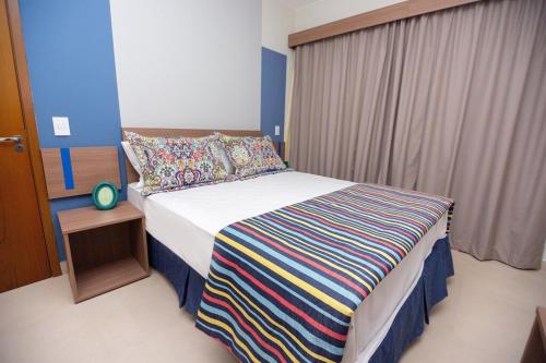 Alta Vista Thermas Resort في كالدس نوفاس: غرفة نوم مع سرير وبطانية مخططة ملونة