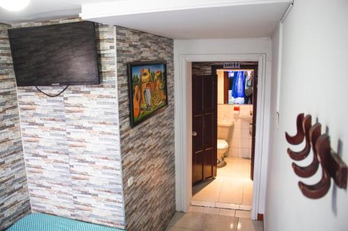 a bathroom with a brick wall and a television on the wall at Hotel Punto 100 in Bogotá