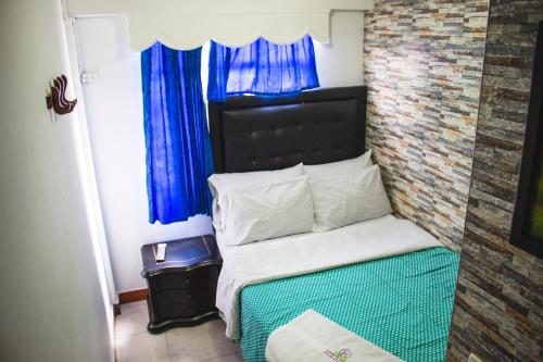 a small bedroom with a bed with blue curtains at Hotel Punto 100 in Bogotá