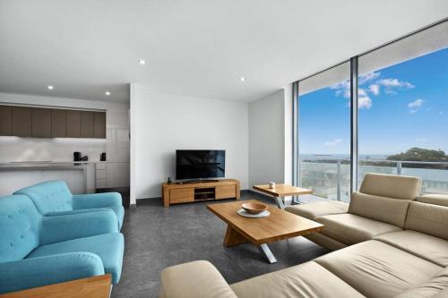 a living room with two blue chairs and a television at Luxury Apartment Caves Beach 4 Bed in Caves Beach