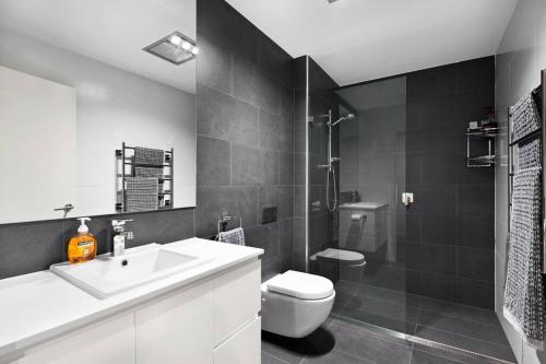 a bathroom with a sink and a toilet and a shower at Luxury Apartment Caves Beach 4 Bed in Caves Beach