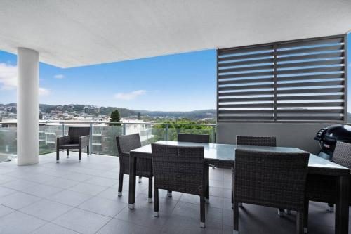 a dining room with a table and chairs and a balcony at Luxury Apartment Caves Beach 4 Bed in Caves Beach