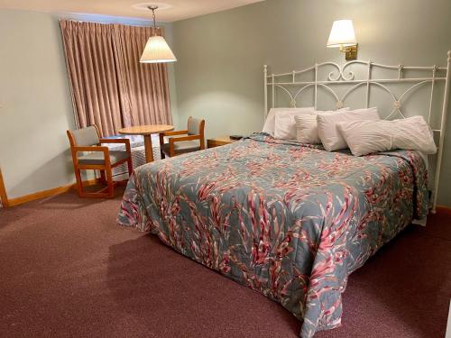 een slaapkamer met een bed en een tafel en stoelen bij Viking Shores Motor Inn in Eastham