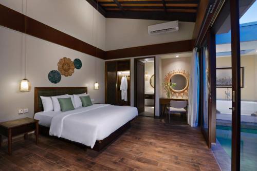 a bedroom with a large white bed and a bathroom at Kamuela Villa Lagoi Bay Bintan in Lagoi