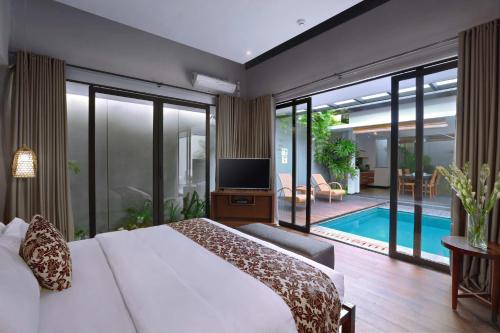 a bedroom with a bed and a tv and a pool at Kamuela Villa Lagoi Bay Bintan in Lagoi